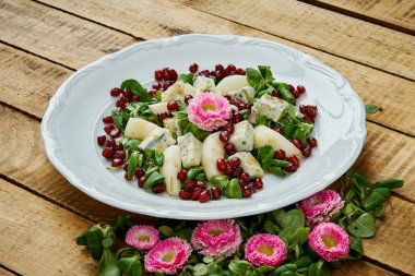 çiçekler ve armut gorgonzola peyniri ve marul üzerine beyaz bir tabak lezzetli bir salata