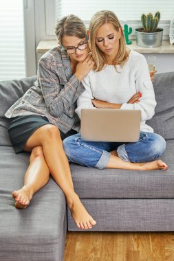 iki kadın ve genç bir bilgisayar ile bir kanepede oturan ve üzgün bir mesaj okuma