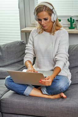güzel genç kadın ve bir bilgisayar ve müzik dinler bir kanepede oturan bir kadın