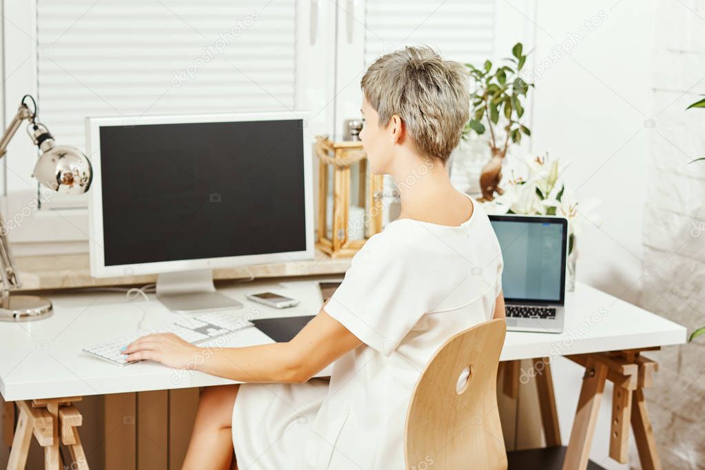beautiful business woman in white dress sitting at desk and working on computer at home office