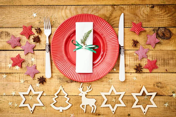 Christmas Eve background on an old wooden table with a red plate with a knife and fork — Stock Photo, Image