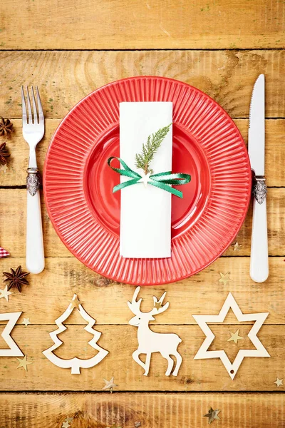 Christmas Eve background on an old wooden table with a red plate with a knife and fork — Stock Photo, Image