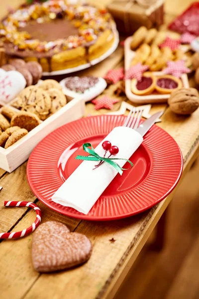 Wooden table with a red plate with knife and fork and various decorations — Stock Photo, Image