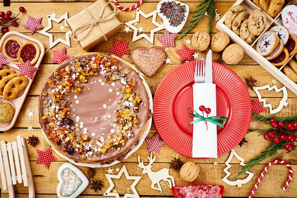 Деревянный стол с вкусными украшениями для рождественских тортов и различными печеньями — стоковое фото
