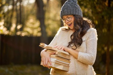 kadın bir kap ve gözlük bir yığın kitap sonbahar orman arka plan üzerinde tutuyor