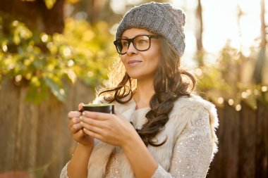 kadın bir kap ve gözlük onun elinde bir fincan kahve, bir sonbahar ormanındaki tutar.