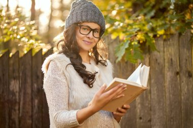 kadın bir kap ve gözlük bir kitap sonbahar ormanda elinde tutuyor