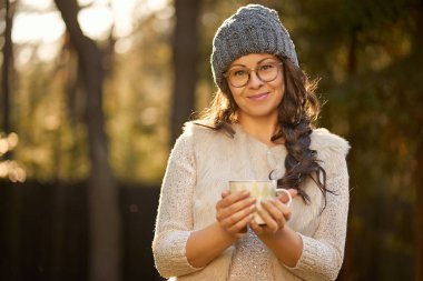 kadın bir kap ve gözlük onun elinde bir fincan kahve, bir sonbahar ormanındaki tutar.