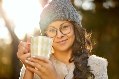 kadın bir kap ve gözlük onun elinde bir fincan kahve, bir sonbahar ormanındaki tutar.
