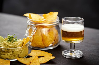 bira ve bir kase guacamole Nacho eski siyah ahşap masa ile