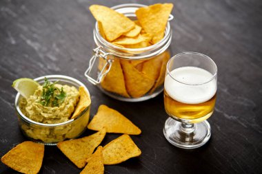 bira ve bir kase guacamole Nacho eski siyah ahşap masa ile