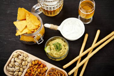 bira ve bir kase guacamole cips ve eski siyah ahşap masa tuzlu atıştırmalıklar ile