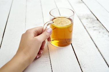kadının el ile bir bardak limonlu eski ahşap masa lezzetli sıcak çay