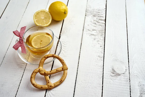 Delicious hot tea with honey and lemon and pretzel on an old wooden table — Stock Photo, Image