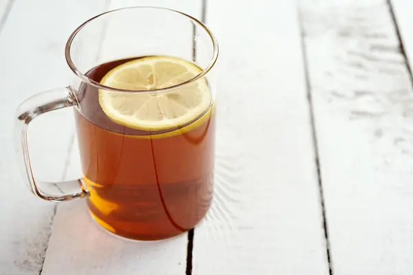 Вкусный горячий чай с медом и лимоном на старом деревянном столе — стоковое фото