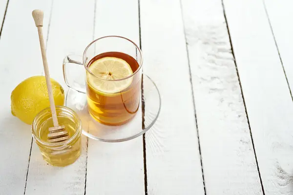 Glass with honey and delicious lemon tea on an old wooden table — Stock Photo, Image