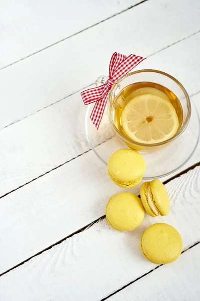 Вид зверху смачні і солодкі макаруни і гарячий лимонний чай на старому дерев'яному столі — стокове фото