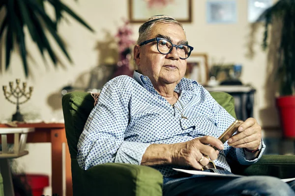 Pensativo judío mayor en el sillón leyendo un libro de la Torá —  Fotos de Stock