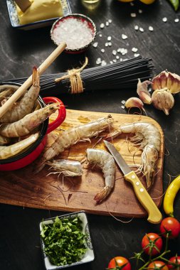 maydanoz, limon, tereyağı ve domates ile kırmızı bir tencerede taze lezzetli çiğ kaplan karides