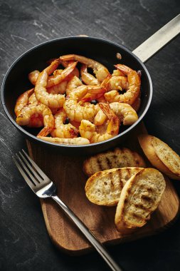 bir tava ve tost ahşap tahta üzerinde taze lezzetli kızarmış karides