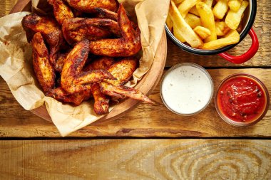 eski ahşap masa üzerinde lezzetli kızarmış tavuk kanadı ve patates kızartması üstten görünüm