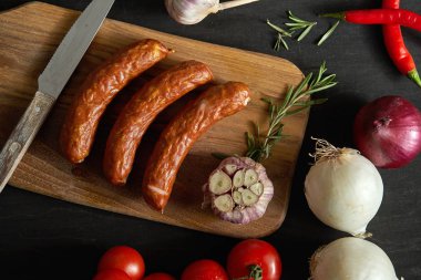 farklı sebze ile üç lezzetli sosis üstten görünüm ahşap bir masa, bıçak siyah bir tablo üzerinde