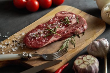 bir ham parça ahşap tahta ve sebze siyah bir tablo üzerinde bir dizi biftek ile tuz, biber