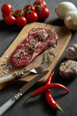 bir ham parça ahşap tahta ve sebze siyah bir tablo üzerinde bir dizi biftek ile tuz, biber