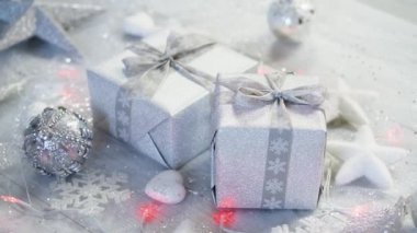 shiny christmas table decoration with two silver presents and lights with snowflakes and white stars