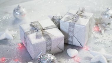 shiny christmas table decoration with two silver presents and lights with snowflakes and white stars