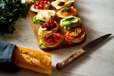 Ahşap tahta ile renkli mini sandviç ya da tapas bir bıçak ve bir masada baget ile birlikte