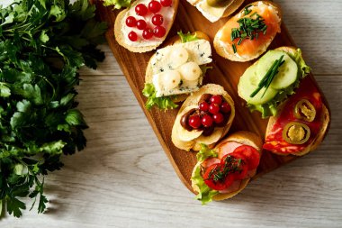 Ahşap tahta ile renkli mini sandviç ya da tapas bir baget ve maydanoz üzerinde masa lambası ile birlikte