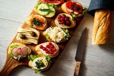 Ahşap tahta ile renkli mini sandviç ya da tapas bir bıçak ve bir masada baget ile birlikte