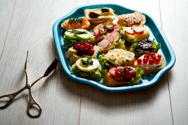 bir grup sağlıklı tapas veya ahşap bir masa üzerinde gıda maşa ile mini sandviç ile eski mavi tepsi