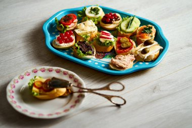 bir grup sağlıklı tapas veya ahşap bir masa üzerinde gıda maşa ile mini sandviç ile eski mavi tepsi