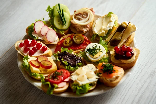 Пластины с красочными и здоровыми бутербродами или тапас на деревянном столе — стоковое фото
