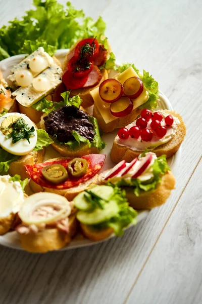 Deska s pestré a zdravé sendviče nebo tapas na dřevěný stůl — Stock fotografie