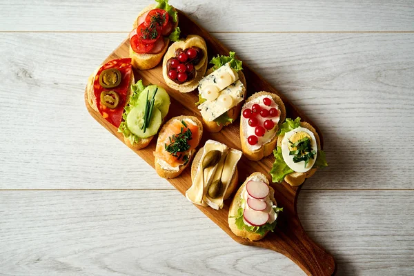 Tavola di legno con mini panini o tapas colorati e sani su un tavolo di legno — Foto Stock