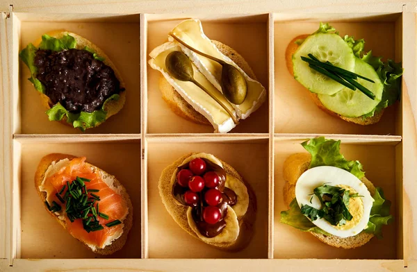Pudełko z zestawem zdrowe kolorowe Kanapki mini lub tapas z warzyw i ryb na stole — Zdjęcie stockowe