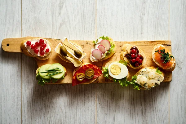 Wooden board with colorful healthy mini sandwiches or tapas on a wooden table — Stock Photo, Image