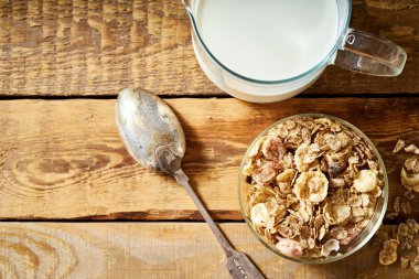 Sağlıklı sabah kahvaltı bir kaşık ve ahşap masa üzerinde süt ile organik granola dolu kase