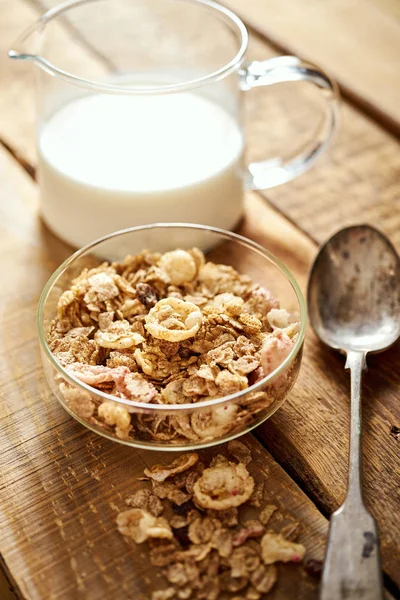 Ciotola sana per la colazione mattutina piena di muesli biologici con cucchiaio e latte sul tavolo di legno — Foto Stock
