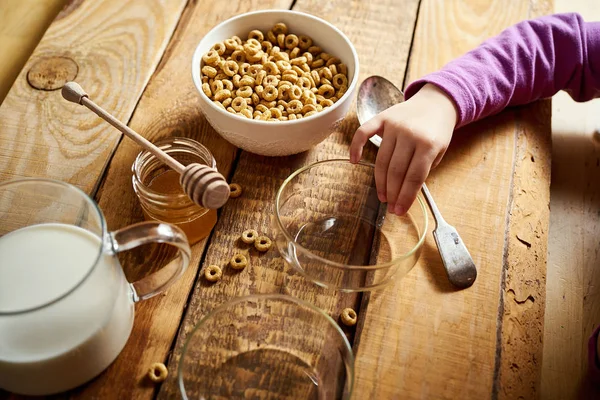 Crianças mão segurando tigela com café da manhã saudável com flocos mel leite e mel dipper na mesa — Fotografia de Stock