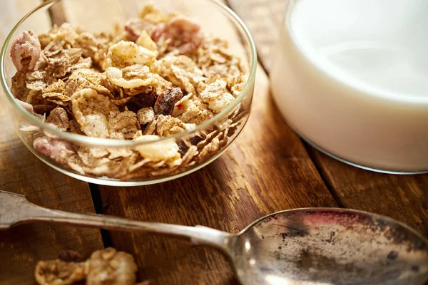 Ciotola sana per la colazione mattutina piena di muesli biologici con cucchiaio e latte sul tavolo di legno — Foto Stock