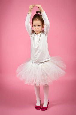sevimli küçük bir kız pembe bir arka plan üzerinde tül etekle portresi