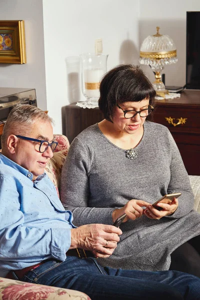 marriage senior couple surfing the net with mobile phone while sitting on the sofa at home.