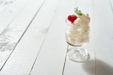 Tatlı taze nane yaprağı ve ahududu Beyaz ahşap masa üzerinde krem şanti ile bardak.