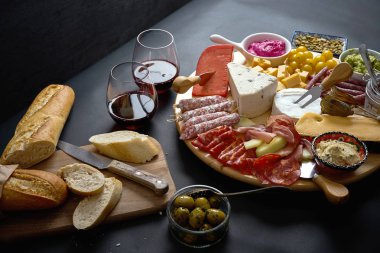 Kırmızı şarap ve siyah masada gemide baget ile peynir ve et aperatifler kurula antipasti