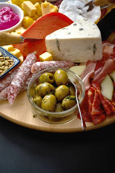 Антипасти с различными сыром и мясом закуски с хумусом и оливками на деревянной круглой доске — стоковое фото