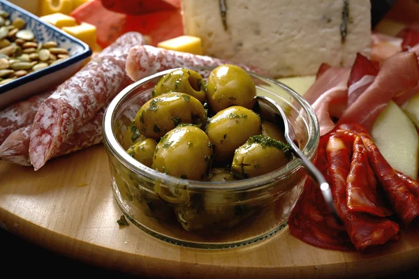Placa antipasti com diferentes queijos e lanches de carne com húmus e azeitonas em tábua de madeira — Fotografia de Stock